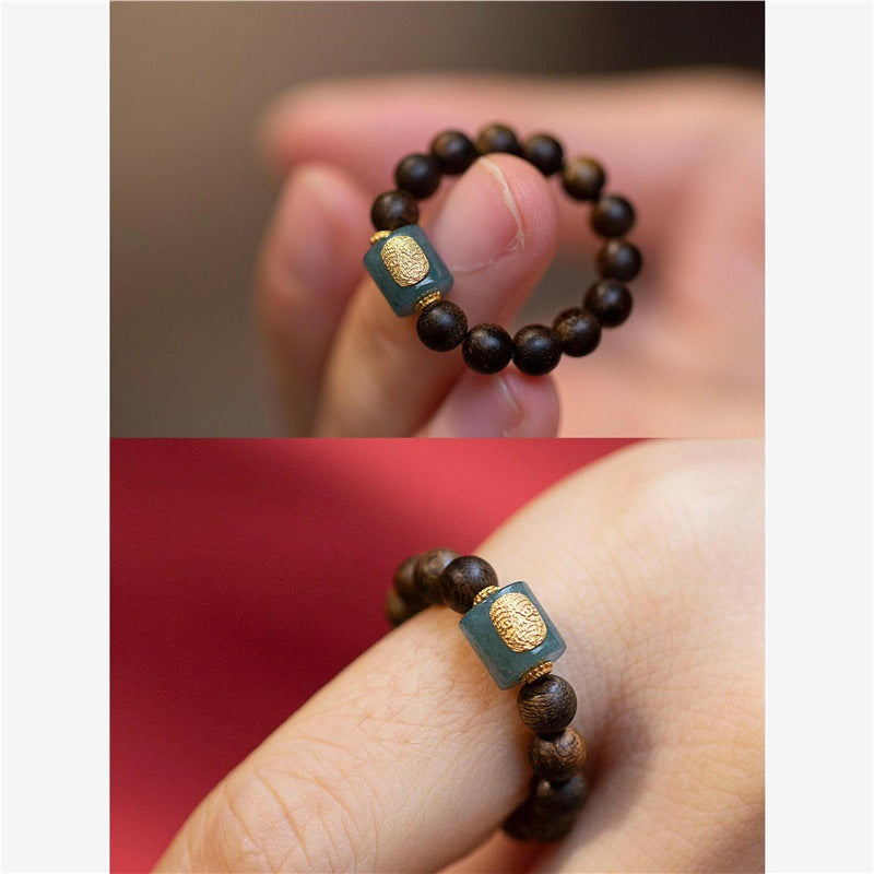 Agarwood Ring – blue jade charm with gold pattern close-up and hand model, red background accent