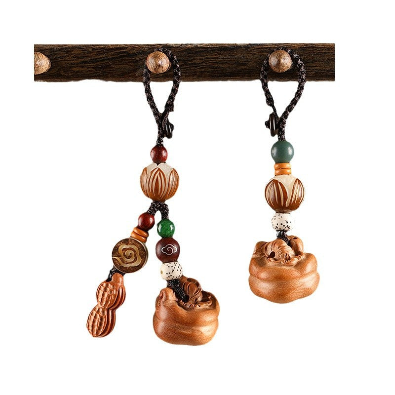 Two peach wood keychain variants hanging on wooden branch against white background