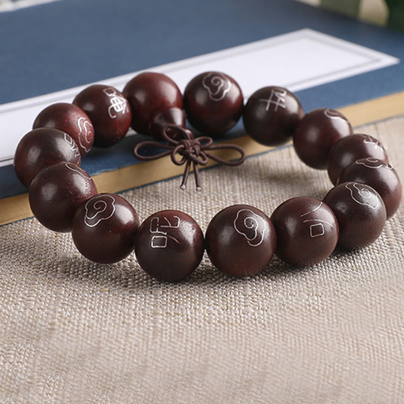 Sterling Silver Sandalwood Mantra Bracelet – curved arrangement with blue book backdrop, carved wood bracelet