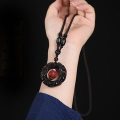 Rainbow Obsidian PiXiu Pendant – Hand holding rainbow obsidian pendant on brown cord necklace
