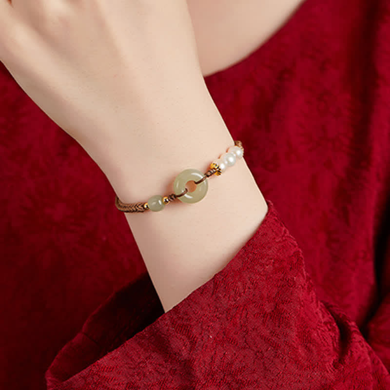 Hetian Jade Pearl Peace Buckle Bracelet – celadon jade disc centerpiece with pearl cluster on braided cord, burgundy velvet lifestyle shot