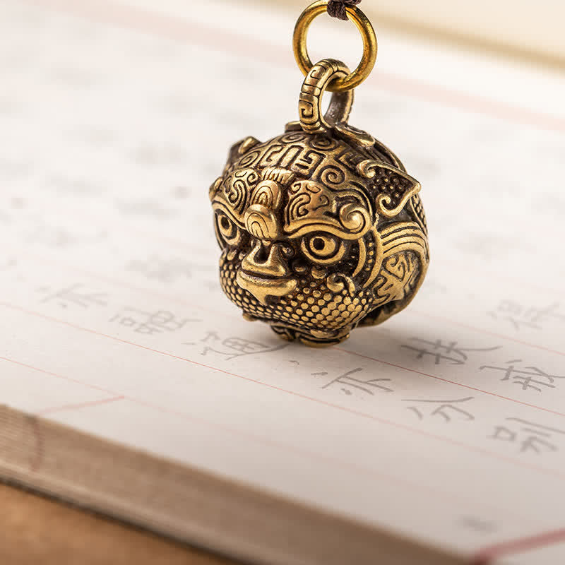 Pixiu Wealth Copper Key Chain – pixiu head close-up on calligraphy paper, intricate brass carving facial details