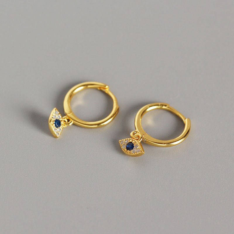 Gold Evil Eye Huggie Hoop Earrings with Blue Stone Pavé Crystals on Gray Background