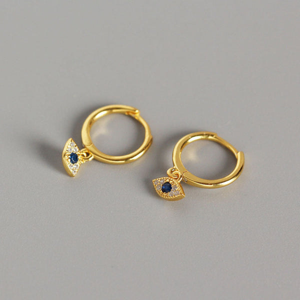 Gold Evil Eye Huggie Hoop Earrings with Blue Stone Pavé Crystals on Gray Background