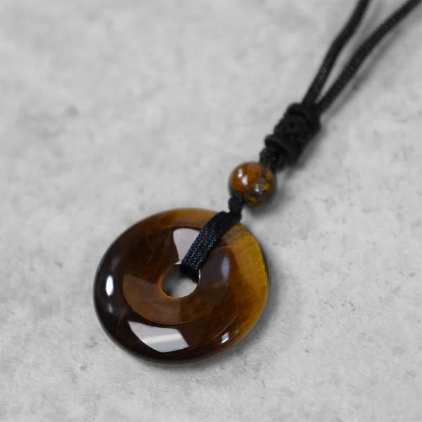 Lucky Coin Pendant Healing Crystal Gemstone Necklace – Tiger's eye peace buckle necklace worn casually over white shirt and gray jacket
