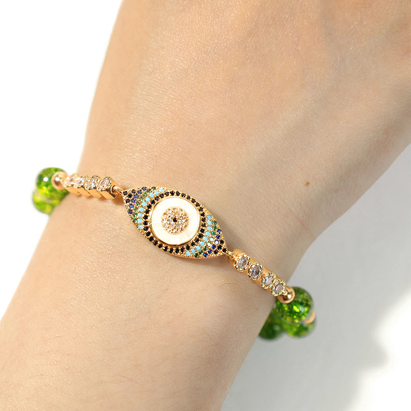Peridot green bead bracelet with crystal evil eye charm worn on wrist, white background