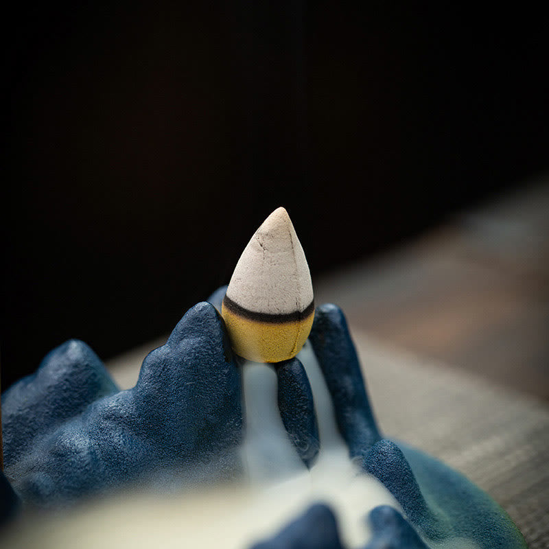 Ceramic Backflow Incense Burner – Close-up of burning cone atop indigo mountain with smoke waterfall, meditation