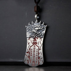 Bagua PiXiu Necklace – Silver talisman with PiXiu head and red cinnabar inscriptions, dark cord, grey wall