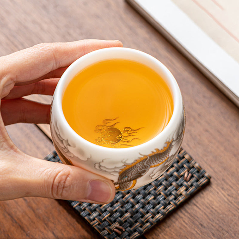Dragon Phoenix Clouds Ceramic Teacup Gift Set – Top-angle, golden pearl motif through amber tea, dragon on exterior, mat