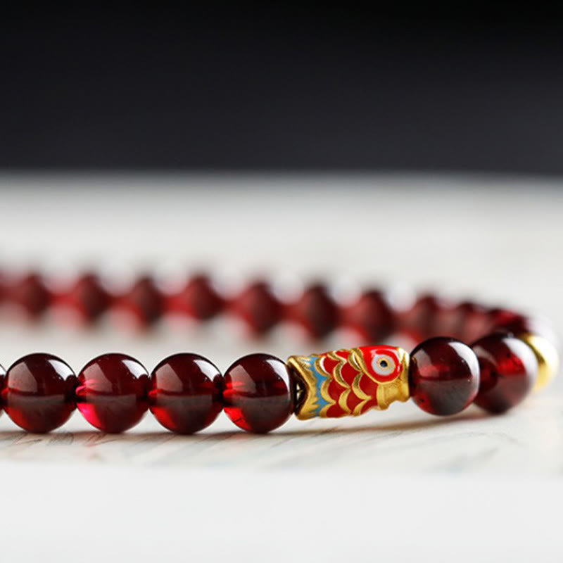 999 Gold Koi Bracelet – draped on velvet display, warm lighting, garnet and gold koi wealth jewelry