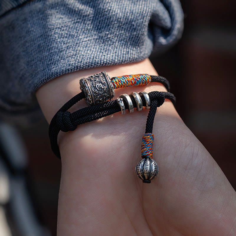Tibetan Om Mani Padme Hum Wrap Bracelet – Hand with blue nail polish holding bracelet showing silver bead and colorful woven segments