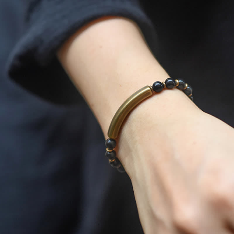 Black obsidian bracelet worn on wrist, matte black stone beads with antique brass centerpiece bar and gold spacers, men unisex everyday jewelry