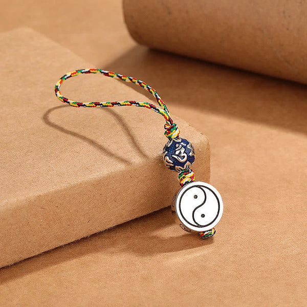Yin Yang Bagua Keychain – Draped over kraft paper block showing natural hang of five-color braided cord with copper pendant