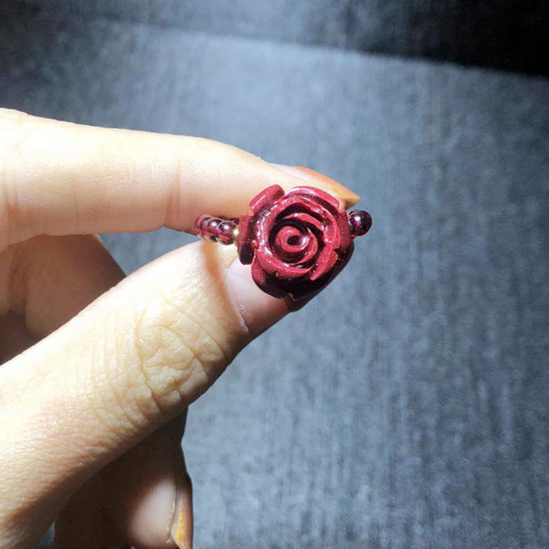 Garnet Cinnabar Ring – hand holding cinnabar rose ring close up carved petal, love charm