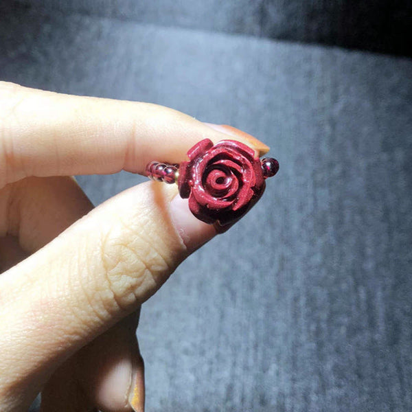 Garnet Cinnabar Ring – hand holding cinnabar rose ring close up carved petal, love charm