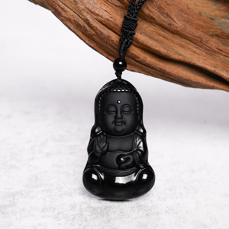 Black Obsidian Buddha Amulet - glossy carved black Buddha on braided cord with driftwood prop, studio shot, Fearless