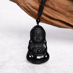 Black Obsidian Buddha Amulet - glossy carved black Buddha on braided cord with driftwood prop, studio shot, Fearless