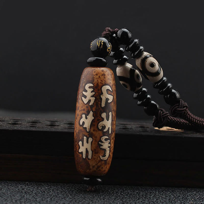 Dzi Bead Necklace – Mantra-engraved brown agate pendant with eye-pattern dzi beads on dark cord, spiritual