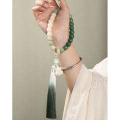 Bodhi Seed Lotus Wisdom Wrist Mala – Ombre bead bracelet worn with silver cuff on hand, lotus tassel and jade gradient, mindfulness jewelry