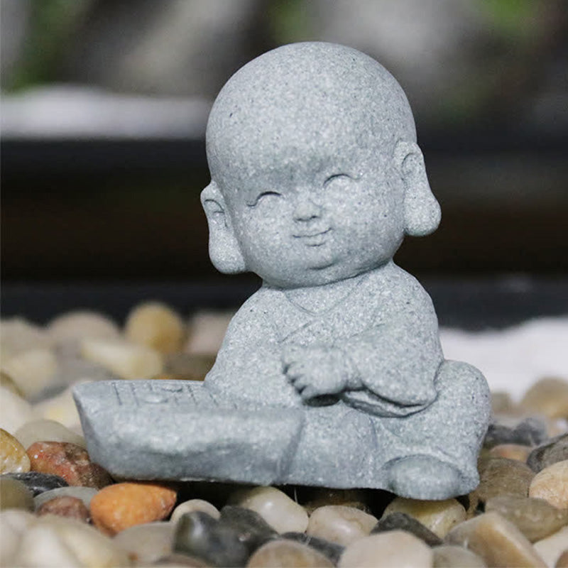 Meditation Monk Statue - Smiling monk playing board game on pebbles, outdoor garden setting