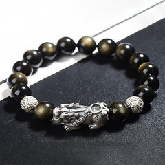 Gold Sheen Obsidian PiXiu Bracelet – Close-up of black beads with silver PiXiu and coin beads on dark surface