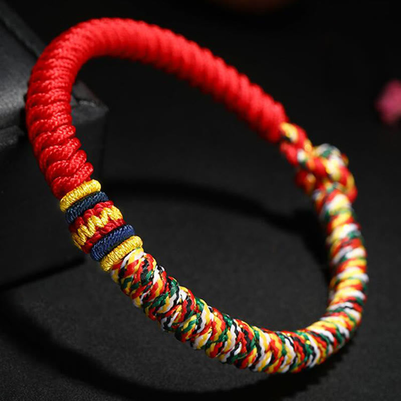 Close-up of Tibetan five-color king kong knot bracelet displaying vibrant red coiled cord with intricate multicolor braided section and decorative gold blue accent bands