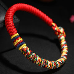 Close-up of Tibetan five-color king kong knot bracelet displaying vibrant red coiled cord with intricate multicolor braided section and decorative gold blue accent bands