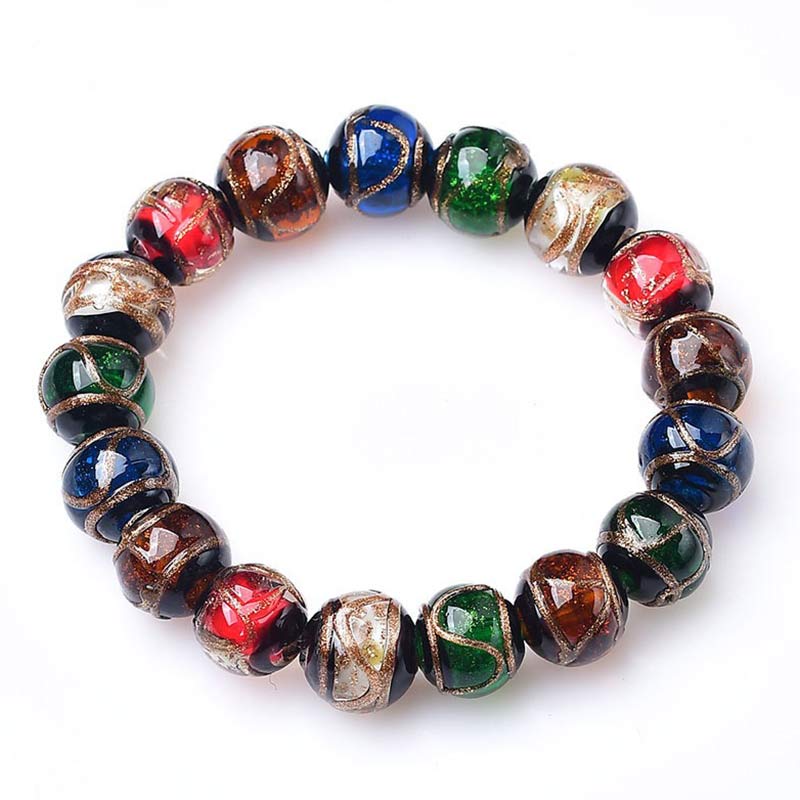 Colorful Liuli Glass Bead Luck Bracelet – Multicolor glass bead bracelet with gold clasp on cream pleated circular paper fan display, gray-blue backdrop, overhead flat lay
