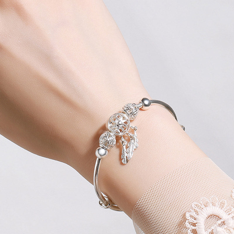 Dream Catcher Blessing Bracelet – Silver charm bangle on wrist against white with lace, crystal detail shot