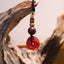 Cinnabar Peace Buckle Keychain – Red carved PiXiu pendant hanging on driftwood branch with beads