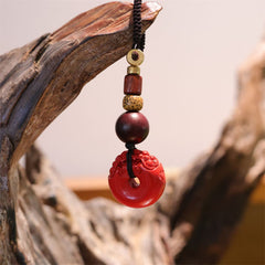 Cinnabar Peace Buckle Keychain – Red carved PiXiu pendant hanging on driftwood branch with beads