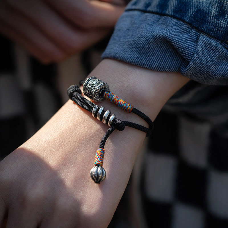 Tibetan Om Mani Padme Hum Wrap Bracelet – Close-up of silver cylindrical bead with Om Mani Padme Hum engraving and floral pattern, beige background
