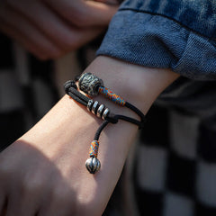 Tibetan Om Mani Padme Hum Wrap Bracelet – Close-up of silver cylindrical bead with Om Mani Padme Hum engraving and floral pattern, beige background