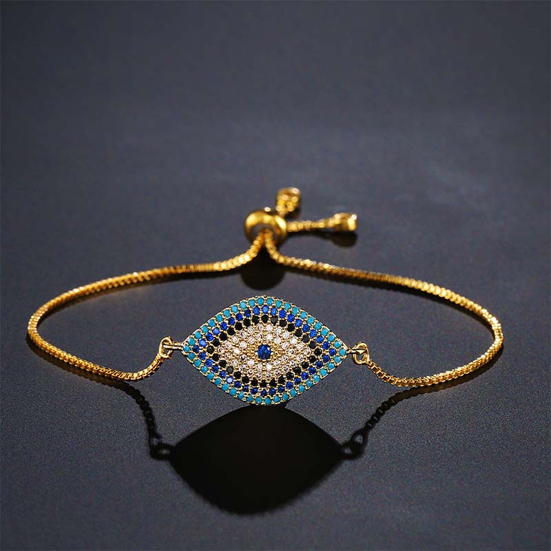Evil Eye Healing Bracelet – Gold tone bracelet with navy turquoise evil eye on dark gray background