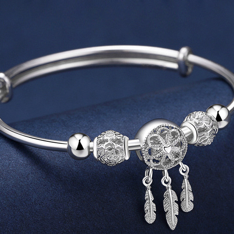 Dream Catcher Blessing Bracelet – Low angle silver bangle on navy velvet with feather charms, charm detail