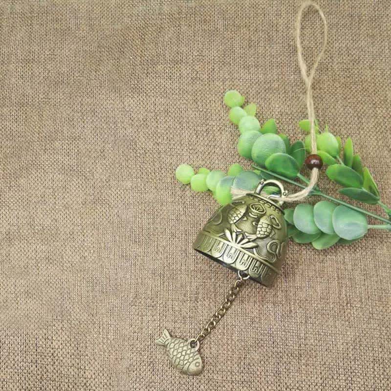 Feng Shui Wind Chime Bell - Top-down view of bronze koi fish bell on burlap with greenery, prosperity