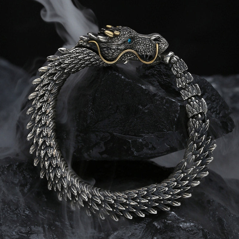 Dragon head bracelet with three gold horns gold whiskers blue turquoise eye and textured scales on dark stone surface with atmospheric fog styling