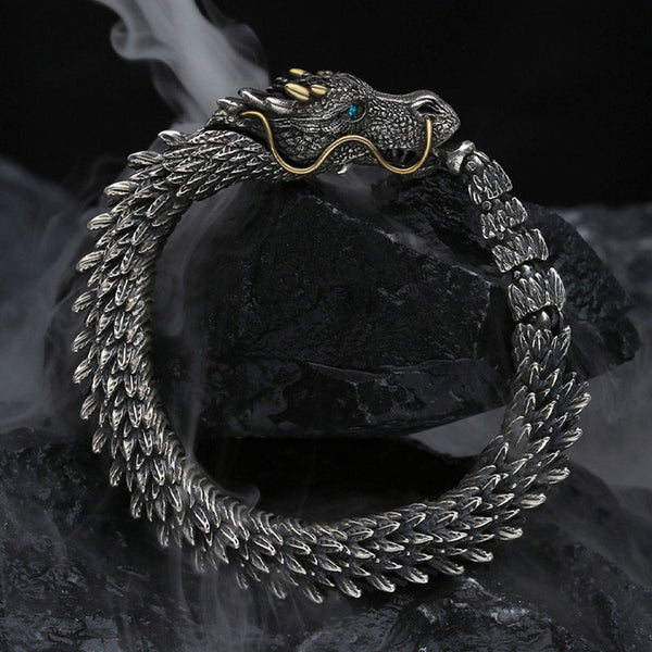Dragon head bracelet with three gold horns gold whiskers blue turquoise eye and textured scales on dark stone surface with atmospheric fog styling