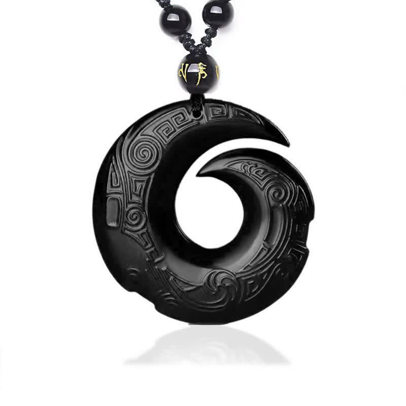 Black Obsidian Ice Obsidian Pendant Necklace – Black polished obsidian spiral carved pendant with intricate Greek key and cloud scroll relief patterns, gold character accent bead, black braided cord, white studio background, obsidian healing crystal jewelry