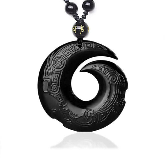 Black Obsidian Ice Obsidian Pendant Necklace – Black polished obsidian spiral carved pendant with intricate Greek key and cloud scroll relief patterns, gold character accent bead, black braided cord, white studio background, obsidian healing crystal jewelry