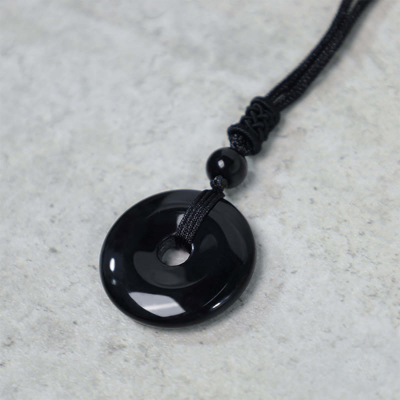 Lucky Coin Pendant Healing Crystal Gemstone Necklace – Solid black obsidian donut pendant on adjustable black cord, gray background