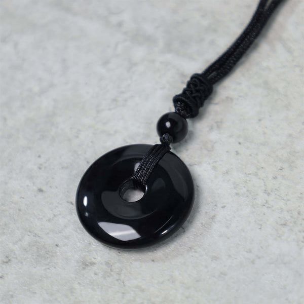 Lucky Coin Pendant Healing Crystal Gemstone Necklace – Solid black obsidian donut pendant on adjustable black cord, gray background