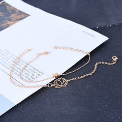 Lotus Heart Enlightenment Bracelet - Rose gold lotus and heart anklet on dark speckled surface, purity jewelry