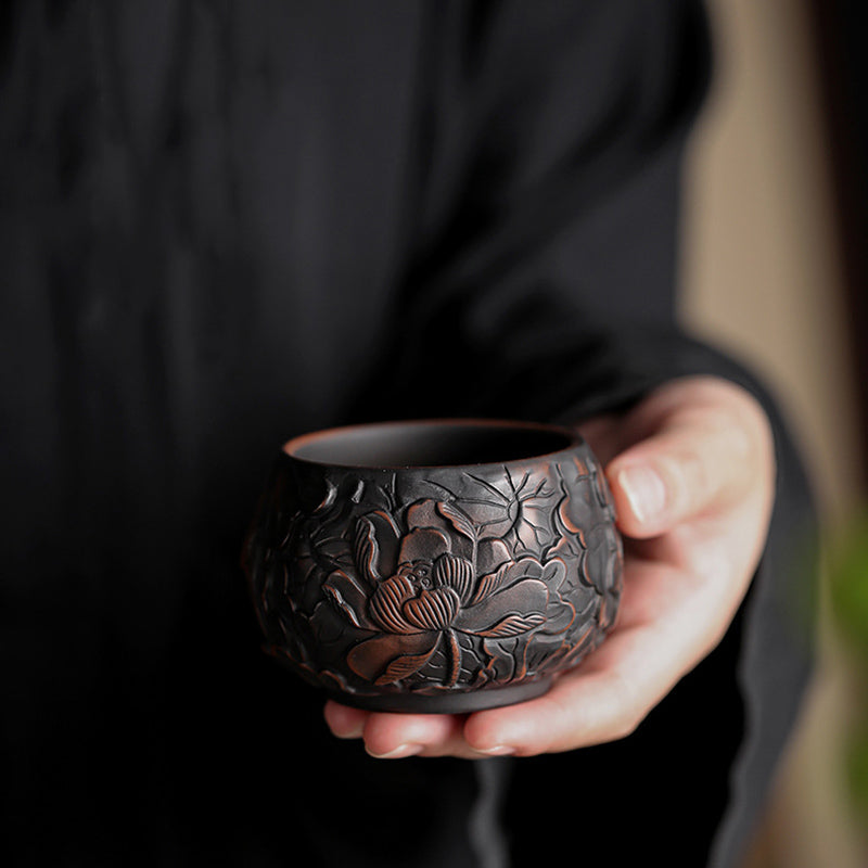 Ceramic Tea Cup – Hand holding carved lotus relief on bamboo tray, artisan tea ware