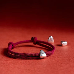 925 Silver Fu Character Braided Bracelet – Red twisted cord bracelet with silver fortune charm and adjustable sliding knot, red textured background flat lay overhead