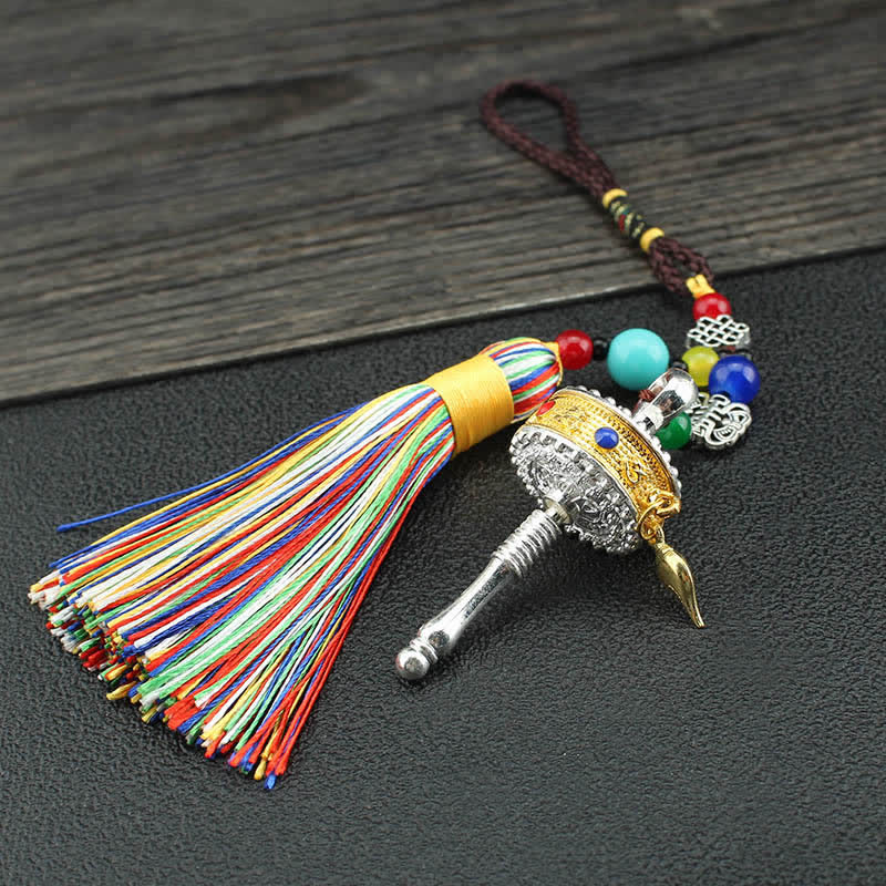 Tibetan Prayer Wheel Tassel – Prayer wheel charm with gemstone inlays and tassel held in hand