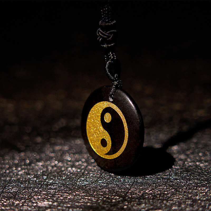 Yin Yang Crystal Necklace – Dark wood oval pendant with gold yin-yang inlay on black cord, textured leather background with d