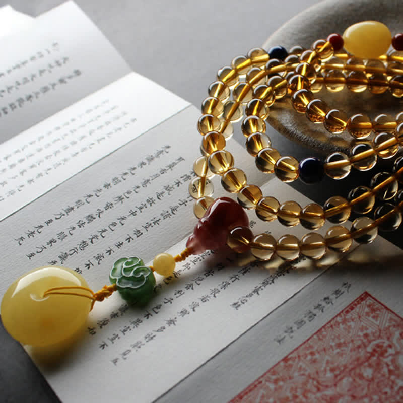 Citrine Mala Bracelet – Citrine mala resting on open calligraphy book with Buddhist scripture