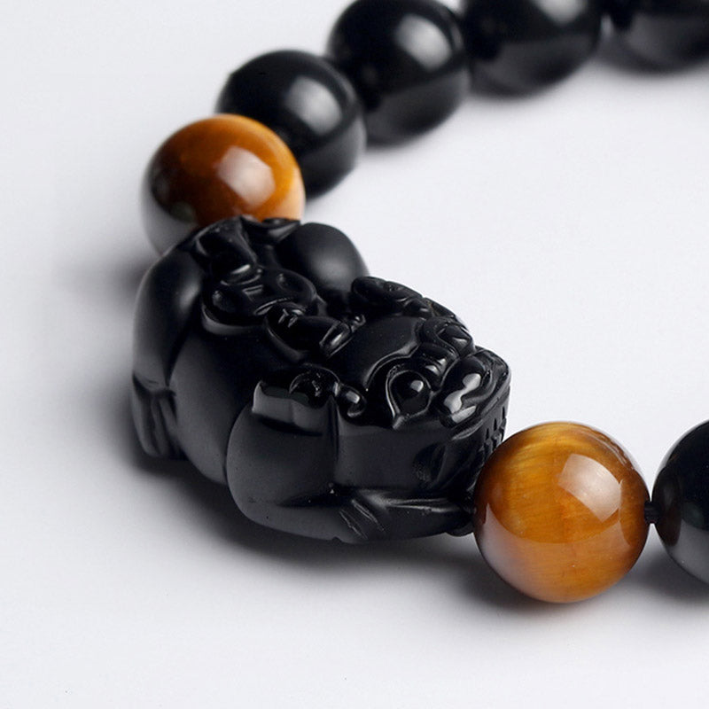 FengShui PiXiu Rainbow Obsidian Bracelet – PiXiu and tiger eye closeup white background, polished black obsidian carving