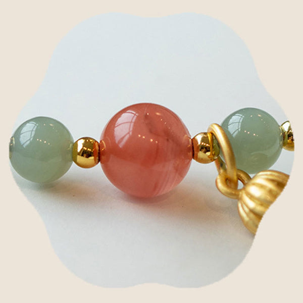 Red Agate Jade Lotus Bracelet – coral pink center bead with jade side beads and gold clasp, low-angle macro bead detail